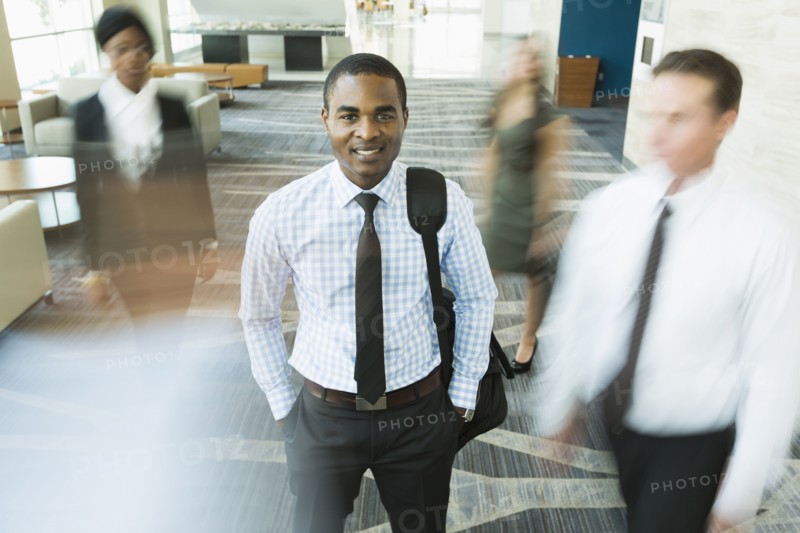 Businessman standing still in busy office lobby
