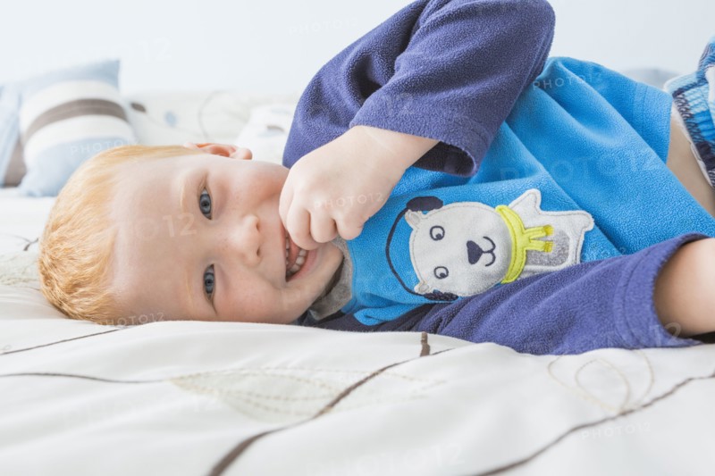 Caucasian boy smiling on bed