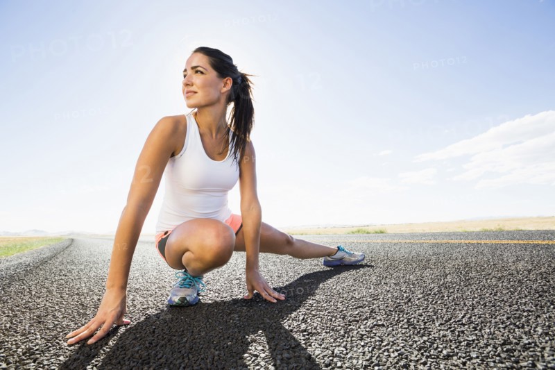 Caucasian runner stretching on remote road