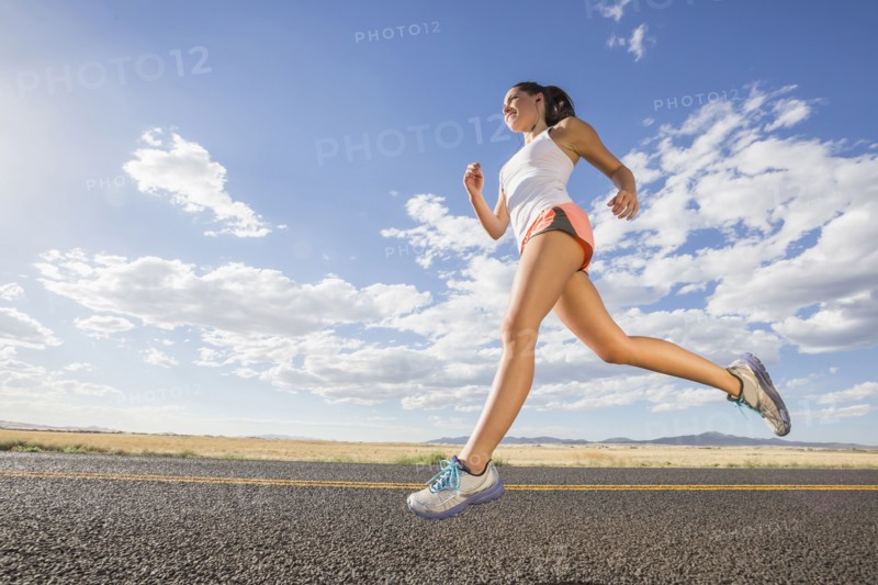 Low angle view of Caucasian woman running on remote road