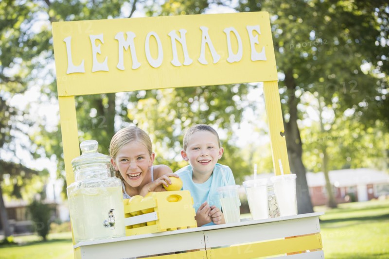Caucasian brother and sister smiling at lemonade stand