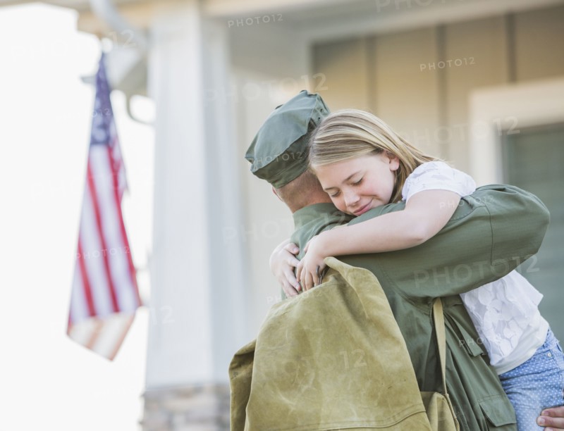Returning Caucasian soldier hugging daughter