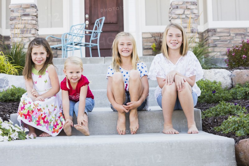 Caucasian sisters smiling on front stoop