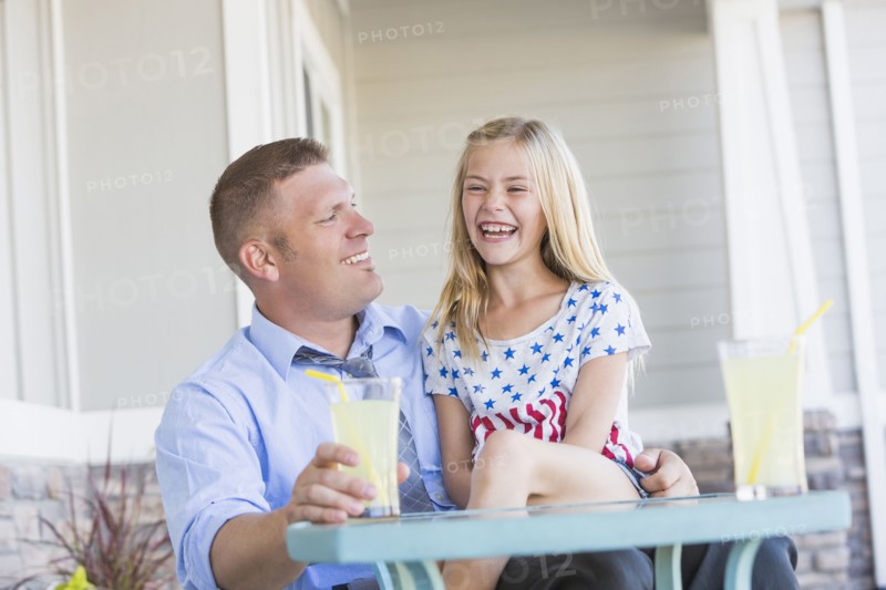 Caucasian father and daughter laughing on porch