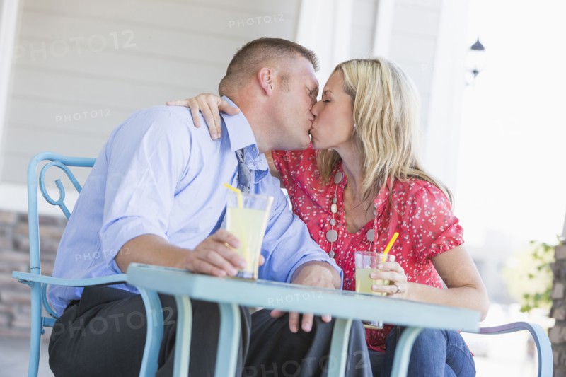 Caucasian couple kissing on porch