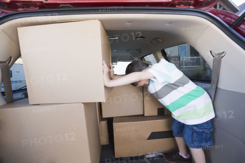 Caucasian boy packing cardboard boxes in car