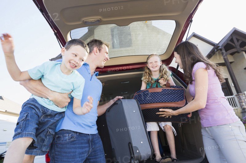 Caucasian family unpacking suitcases from car
