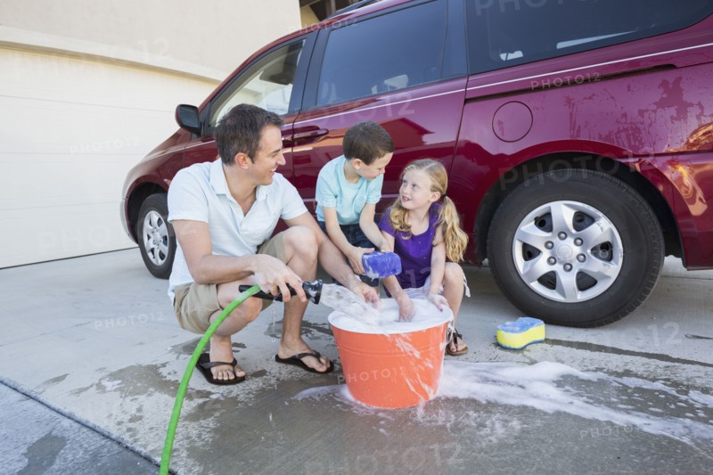Caucasian father and children washing car in driveway