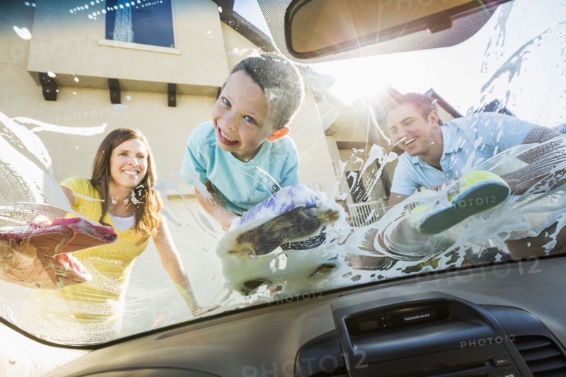 Caucasian father and children washing car windshield