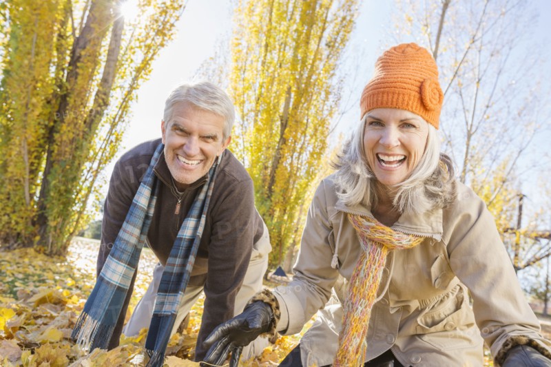 Older Caucasian couple playing in autumn leaves