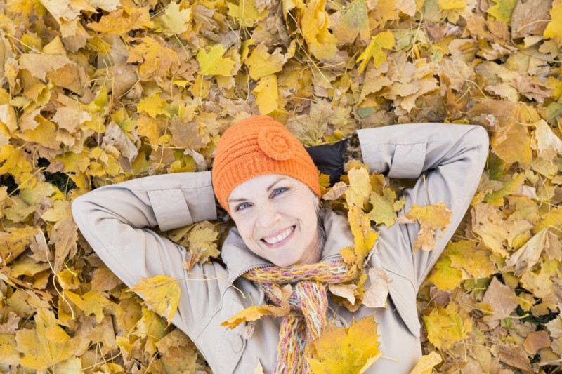 Older Caucasian woman smiling in autumn leaves