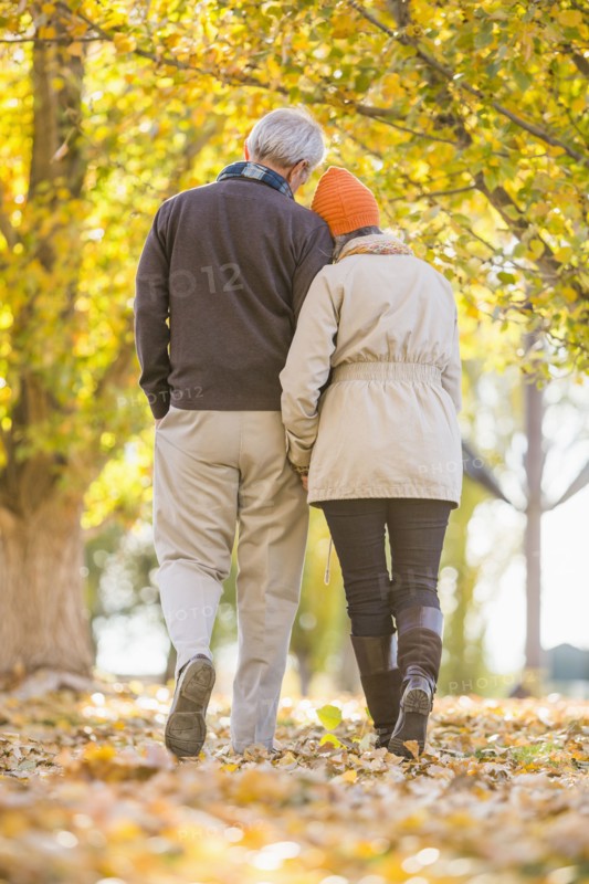 Older Caucasian couple walking under autumn trees