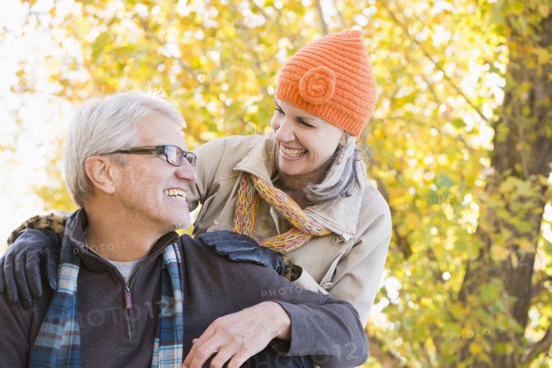Older Caucasian couple smiling under autumn trees