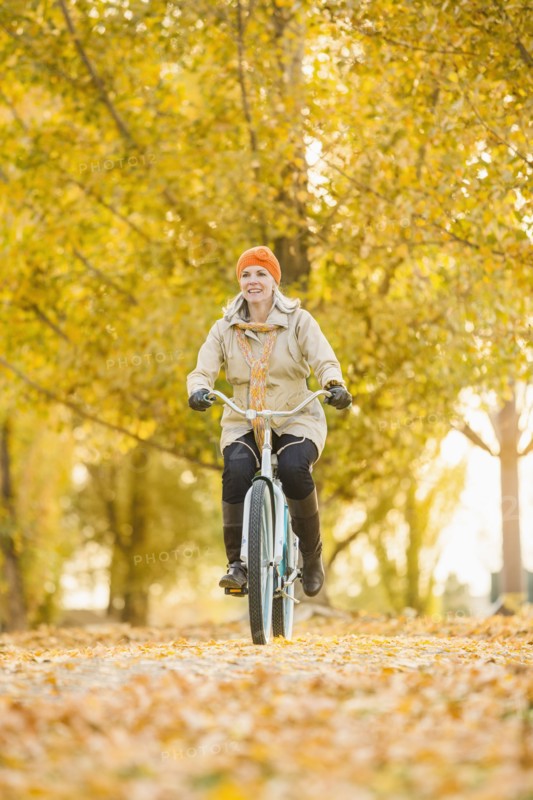 Older Caucasian woman riding bicycle on autumn leaves