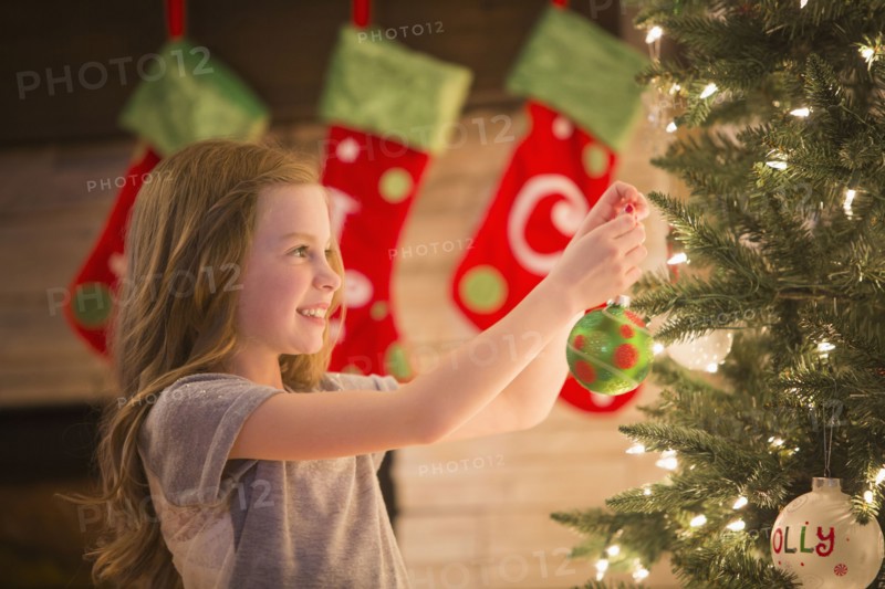 Caucasian girl decorating Christmas tree