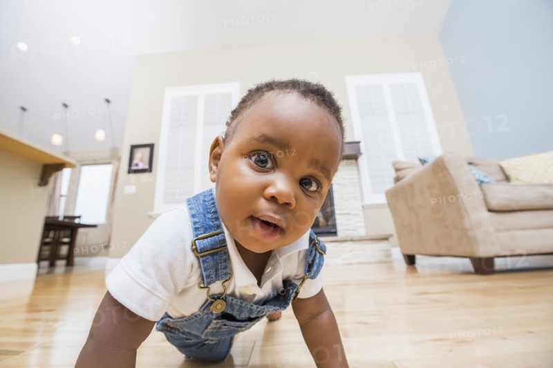 Black baby crawling on living room floor