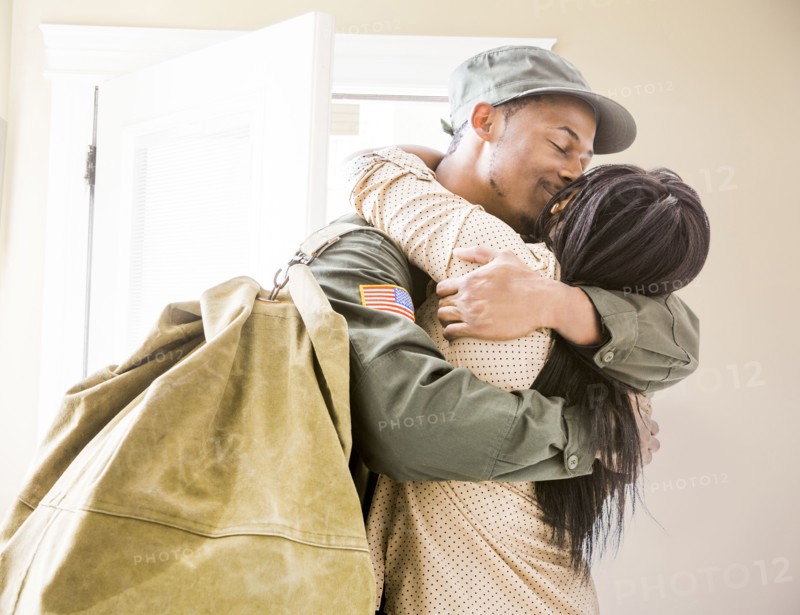 Returning soldier kissing wife in hallway