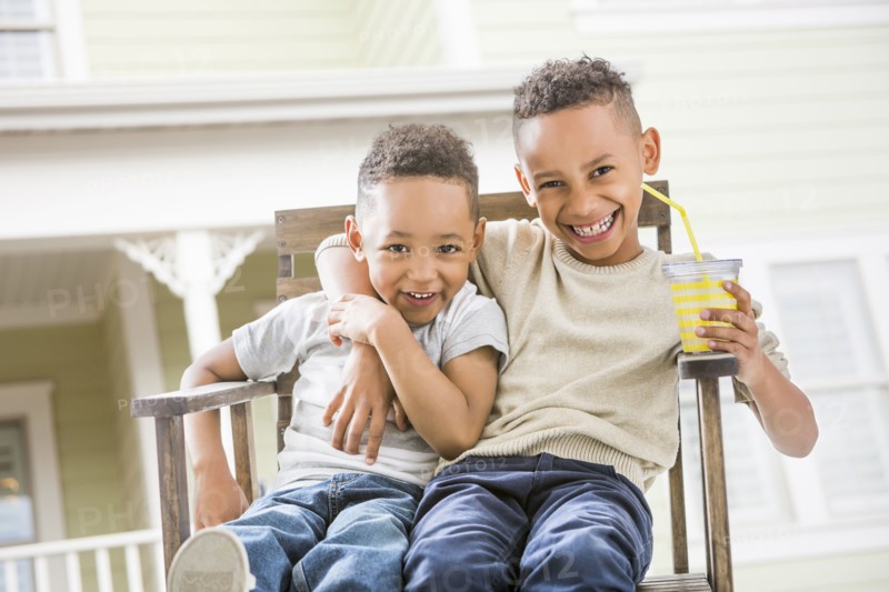 Brothers hugging in armchair in backyard