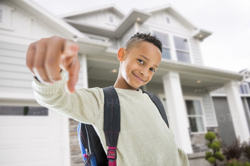 Black boy in backpack pointing on front lawn