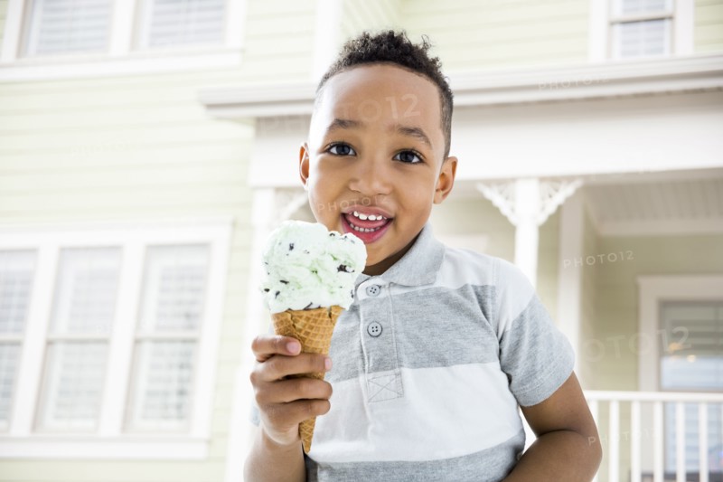 Mixed race boy eating ice cream cone in backyard