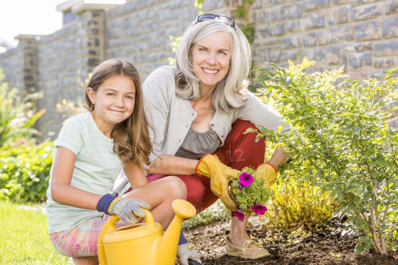 Caucasian grandmother and granddaughter gardening in backyard