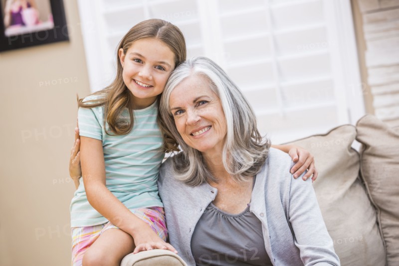 Caucasian grandmother and granddaughter hugging on sofa