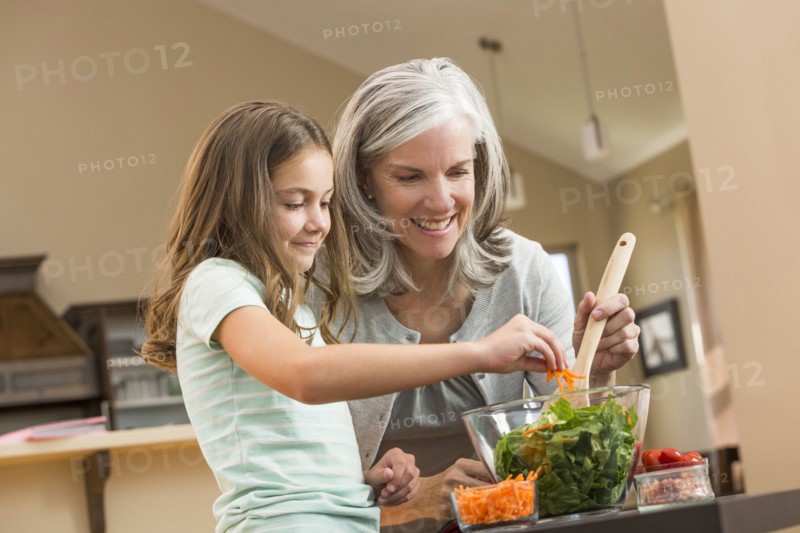 Caucasian grandmother and granddaughter making salad in kitchen