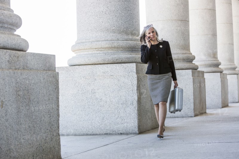 Caucasian businesswoman talking on cell phone under columns