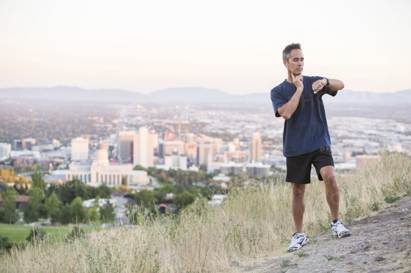 Mixed race man checking pulse on hilltop over Salt Lake City