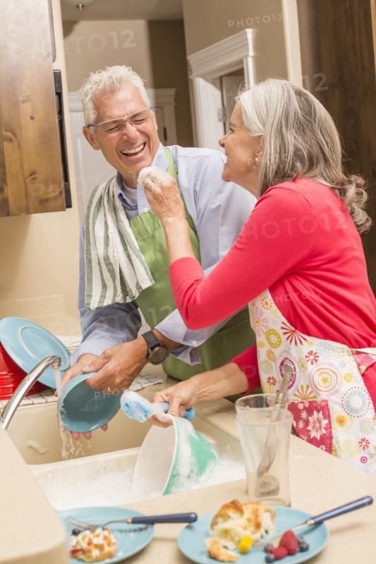 Caucasian couple washing dishes in kitchen