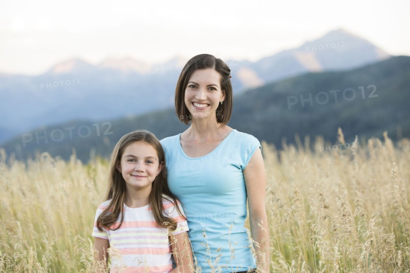 Caucasian mother and daughter smiling in field