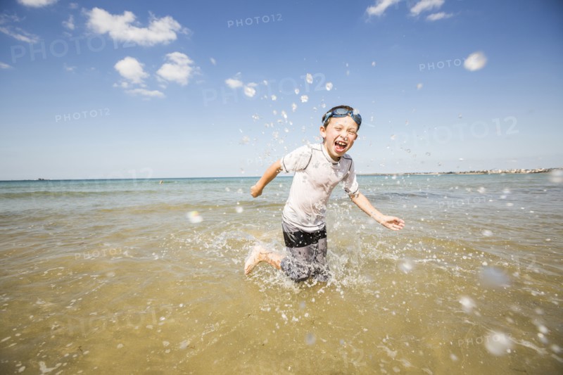 Caucasian boy splashing in waves on beach