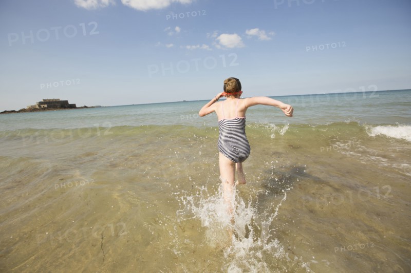 Caucasian girl splashing in waves on beach