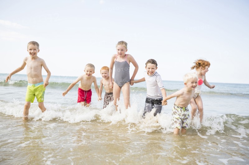 Caucasian children playing in waves on beach