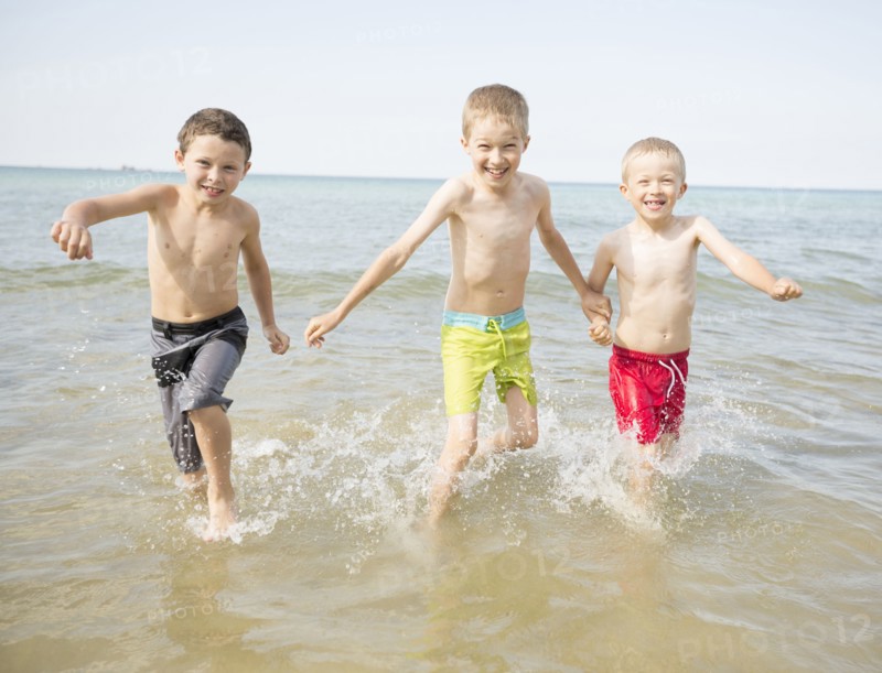 Caucasian boys playing in waves on beach