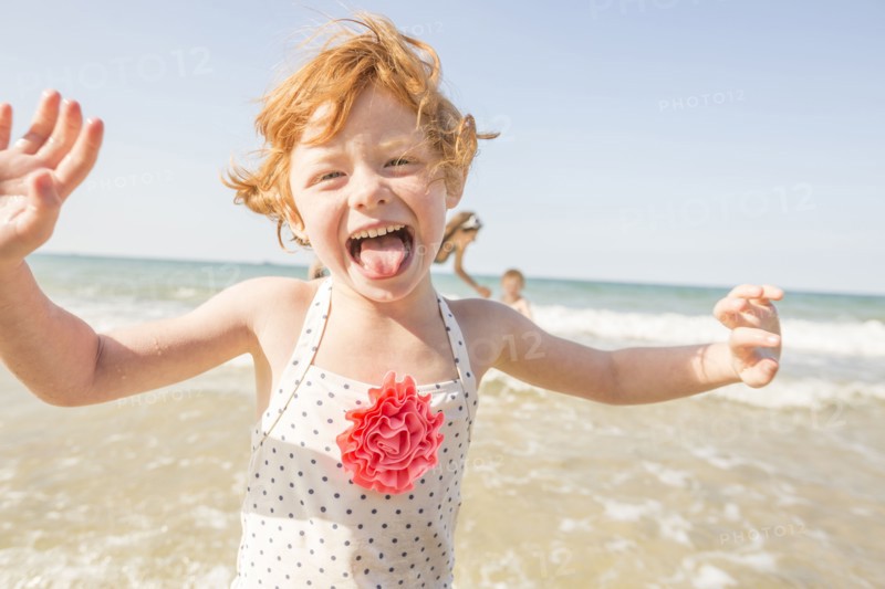 Caucasian girl playing in waves on beach