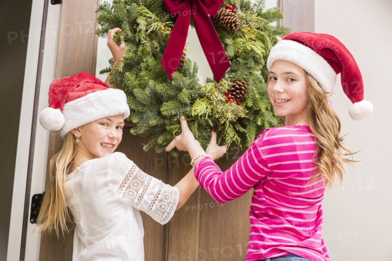 Caucasian girls hanging Christmas wreath