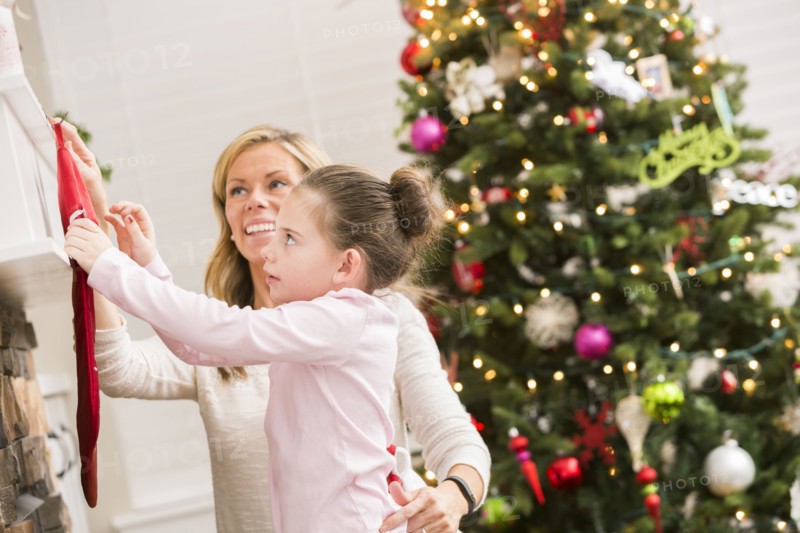 Caucasian mother and daughter hanging Christmas stockings