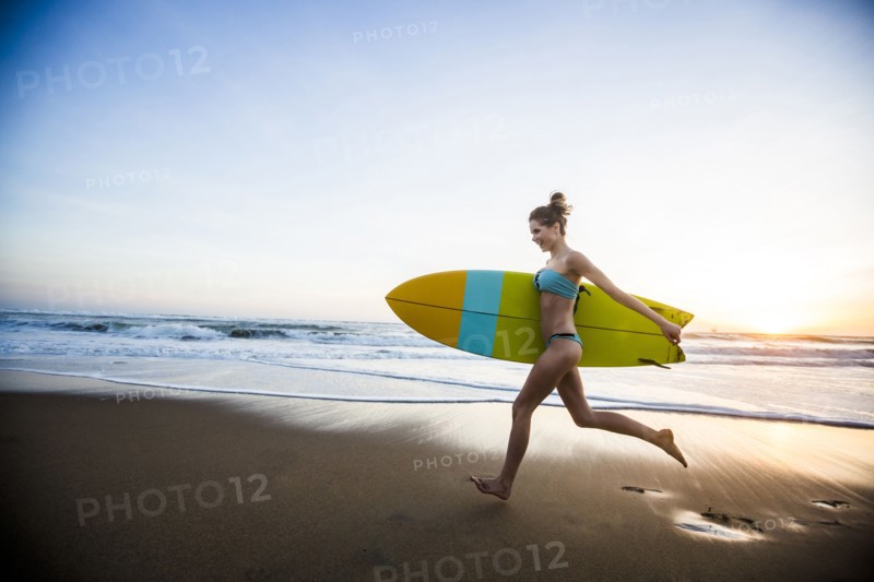Caucasian woman carrying surfboard on beach