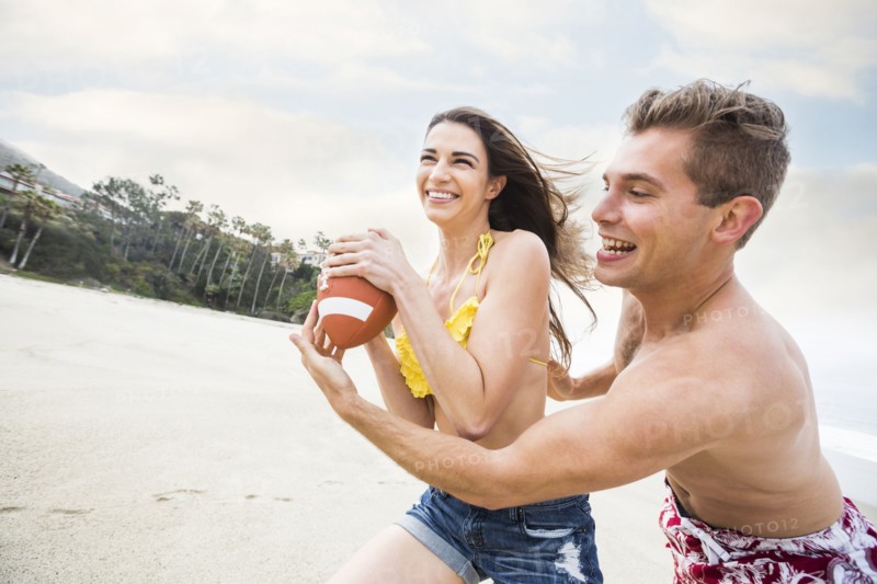 Caucasian couple playing on beach