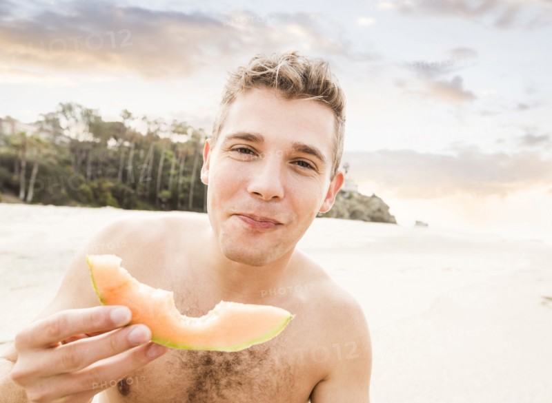 Caucasian man eating fruit on beach