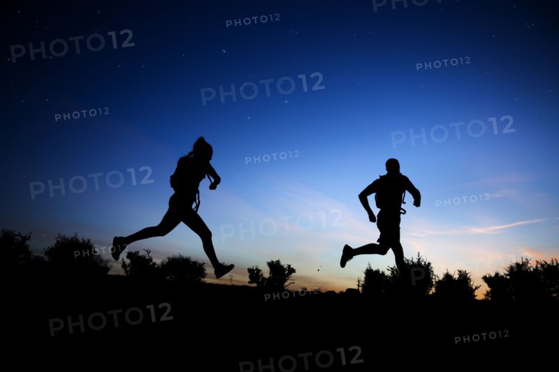 Silhouette of Caucasian couple running at dawn