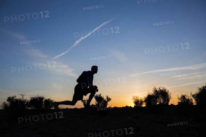 Silhouette of Caucasian teenage boy running at dawn