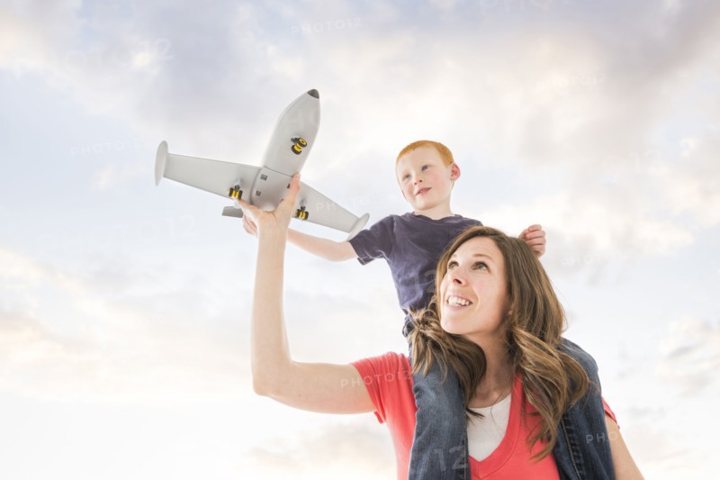 Caucasian mother and son flying toy airplane