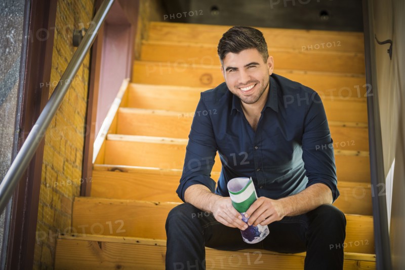 Caucasian man holding paperwork sitting on wooden staircase