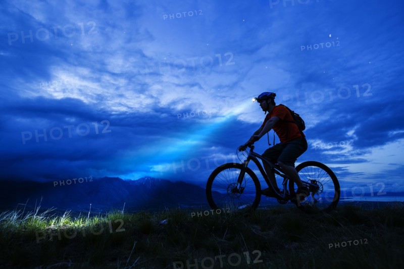 Silhouette of Caucasian man riding mountain bike at night