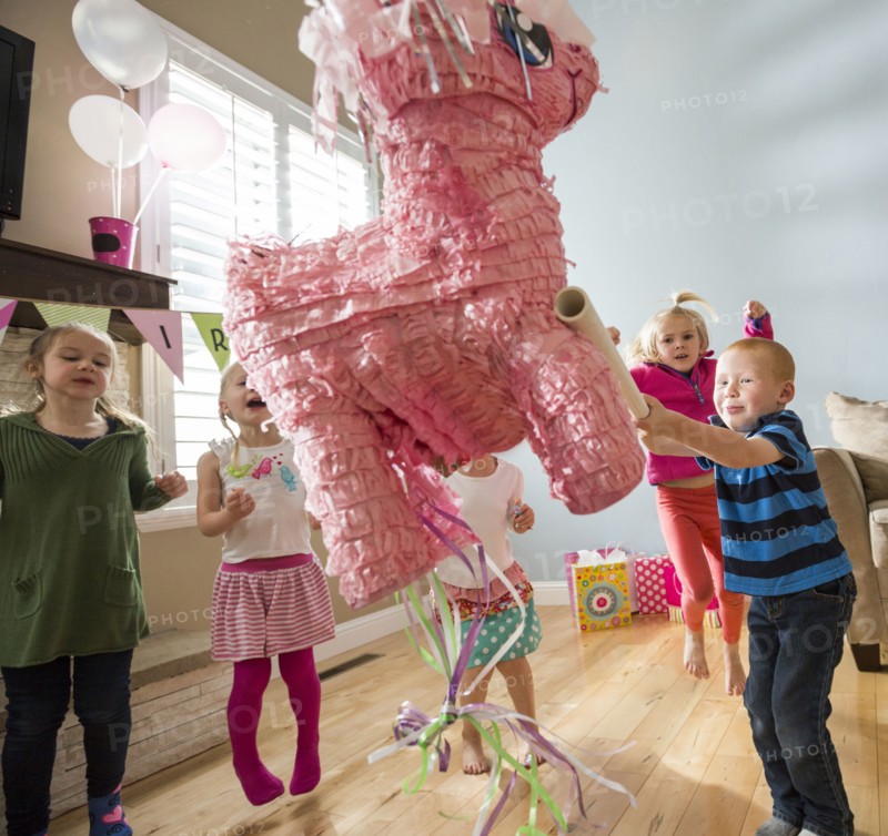Caucasian boy hitting pinata at party