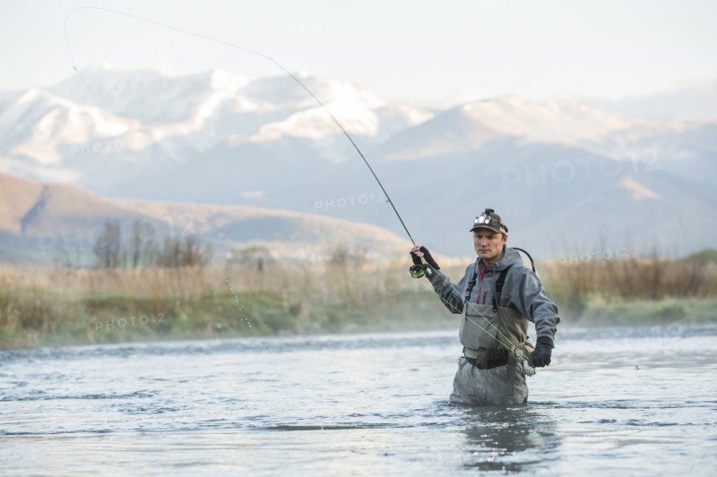 Caucasian man fly fishing in river