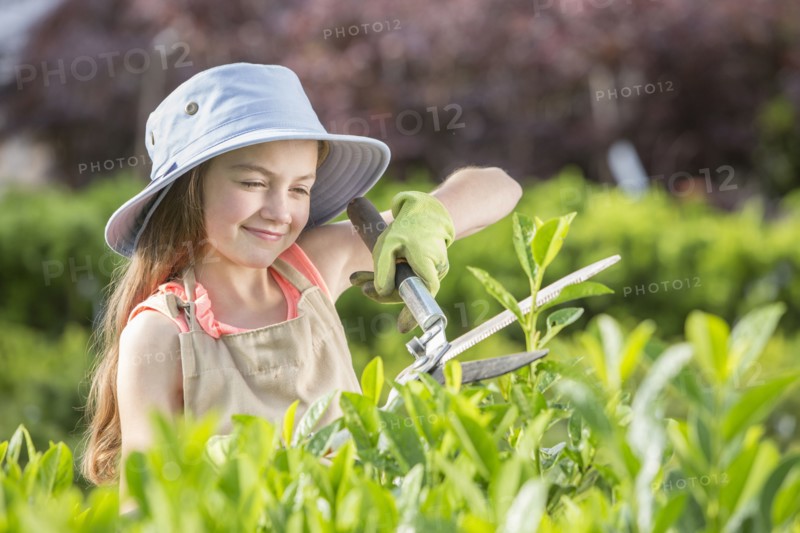 Caucasian girl pruning plants in greenhouse