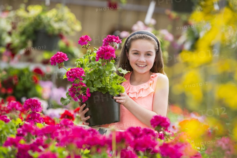 Caucasian girl holding potted plant in greenhouse